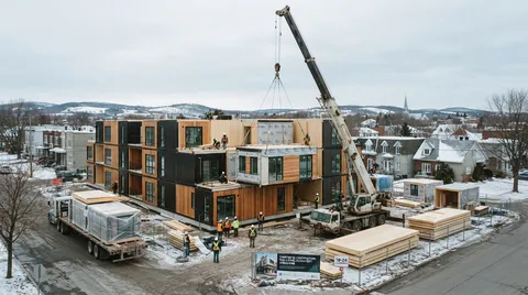 Modules d'un immeuble multilogement levés par une grue et assemblés sur une fondation au Québec